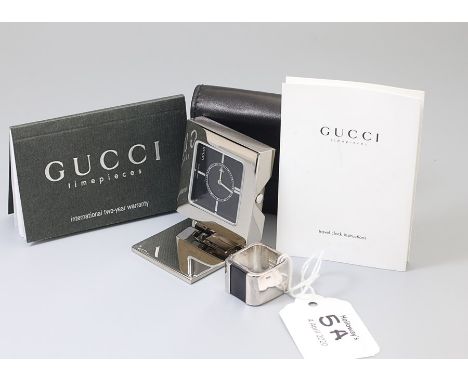 Gucci. A stainless steel travelling clock, the black enamel dial with baton markers and internal minute calibrated dial, fold