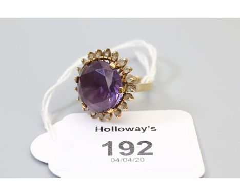 An amethyst dress ring, the large circular cut amethyst within  a border of clear stones, basket mount to a plain shank, mark