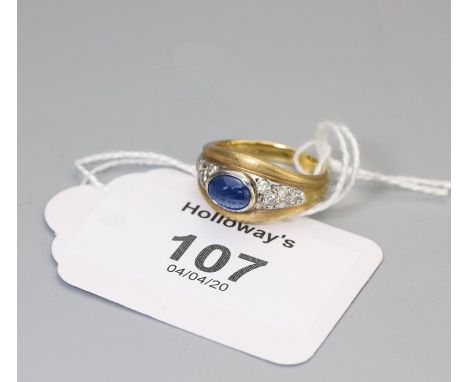 A sapphire and diamond ring, the central oval cabochon sapphire with six stone diamond shoulders contained within a wide text