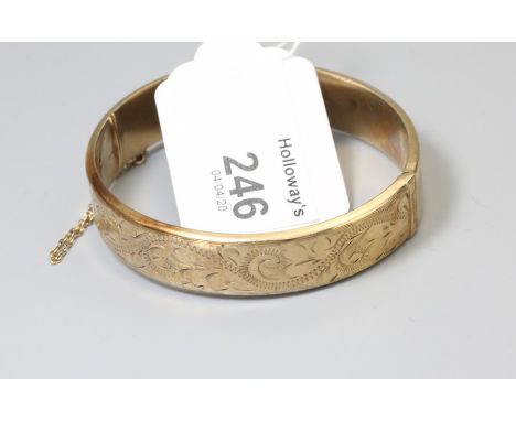 A 9ct gold bangle foliate engraved to centre with push button clasp, 10.68g