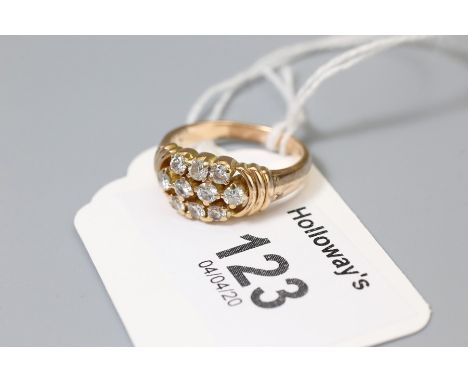A ten stone diamond three tier ring, the brilliant cut diamonds in open work claw mount to reeded and tapering shoulder,  Rin