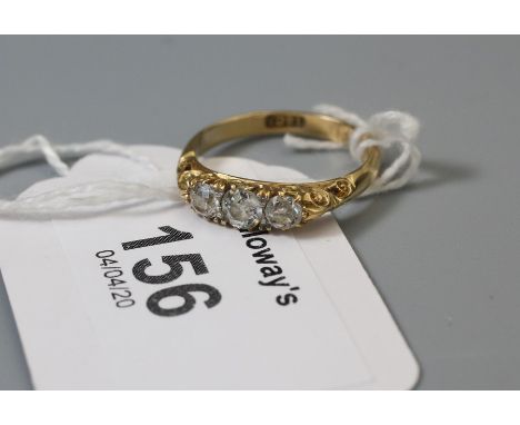 A three stone diamond ring, the slightly graduated old brilliant cut diamonds in pierced and carved mount, marked 18ct Ring s