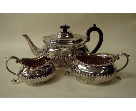 A late Victorian silver three piece tea service of typical oval form with half ribbed decoration, consists of a teapot with e