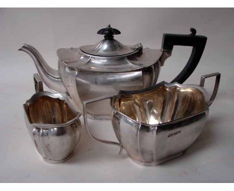 An early 20th century silver three piece tea service of lobed oval form consisting of a teapot with ebonised handles and knop