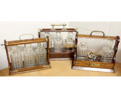 Three White Metal Mounted Bottle Tantaluses, one lacking a decanter