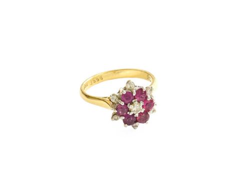 An 18 Carat Gold Ruby and Diamond Cluster Ring, the central round brilliant cut diamond within a border of round cut rubies, 