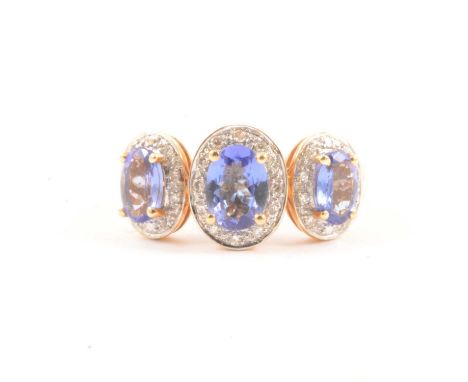 A tanzanite and diamond cluster ring, the central oval mixed cut tanzanite 6.9x5mm and two others oval mixed cut tanzanites a