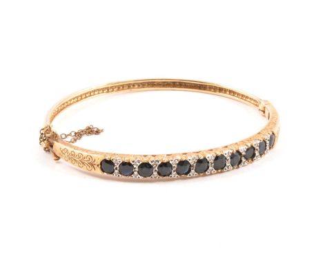 A reproduction Victorian sapphire and diamond half hinged bangle, the eleven sapphires claw set and spaced by ten pairs of 8 