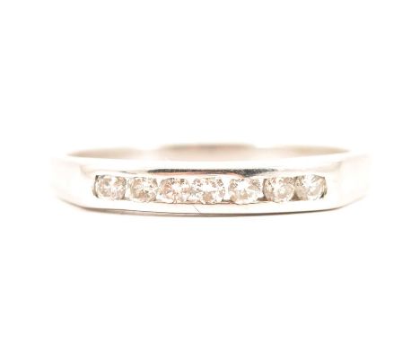 A diamond half eternity ring, seven brilliant cut diamonds channel set in an 18 carat white gold mount, 3.2mm wide, ring size