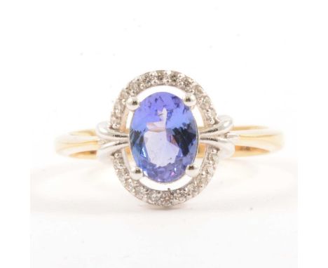 A tanzanite and diamond cluster ring, the oval mixed cut tanzanite 8x6mm, four claw set and surrounded by a halo of twenty-tw
