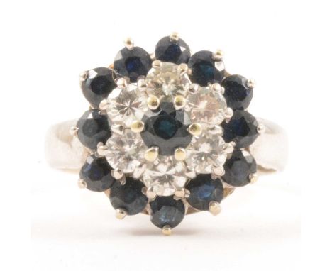 A sapphire and diamond reverse cluster ring, a central sapphire surrounded by six brilliant cut diamonds and outer circle of 