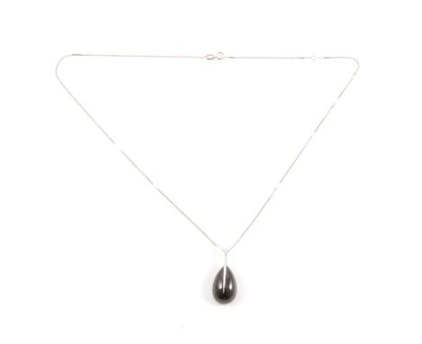 A black onyx and diamond pendant and chain, the 18mm pear shaped black onyx bead held in a 9 carat white gold bar set with sm