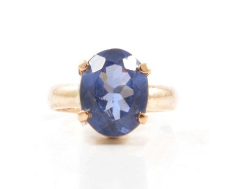 A tanzanite solitaire ring, the oval mixed cut stone four claw set in an all yellow metal mount ring size O, on a 3.8mm wide 