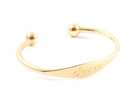 A 9 carat yellow gold open ended torque bangle, 9.5mm bead terminations, 4mm solid tubular section with wider plate engraved 
