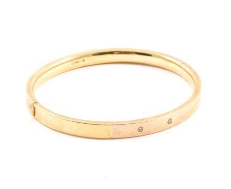A yellow metal modern hollow half hinged bangle, 5.5mm wide plain polished finish inset with two synthetic white stones, inte