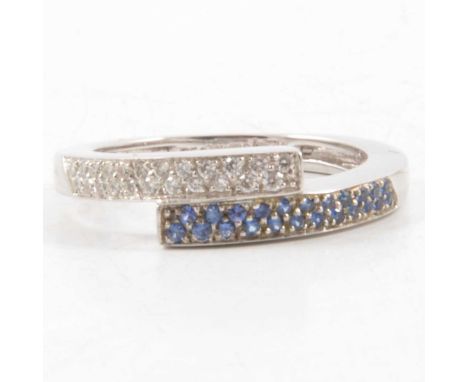 A sapphire and diamond crossover ring size M, twenty three sapphires set to one side, twenty-three brilliant cut diamonds to 