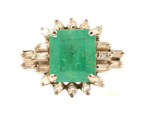 An emerald and diamond ring, the rectangular step cut emerald 9.5 x 8.2mm, four claw set with five 8 cut diamonds to top and 