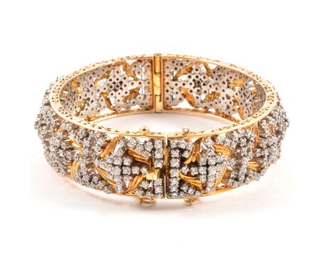 A yellow metal bangle set with multiple synthetic white stones, 17mm wide half hinged design, gross weight 75.5g.