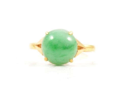 A jadeite solitaire ring, the 10.5mm circular cabochon cut stone four claw set in an all yellow metal mount ring size Q, shan