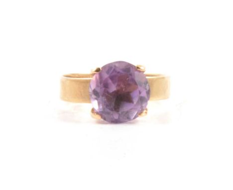 An amethyst solitaire ring, the circular 10mm stone four claw set and mounted on a 9 carat yellow gold 3.7mm wide band ring s