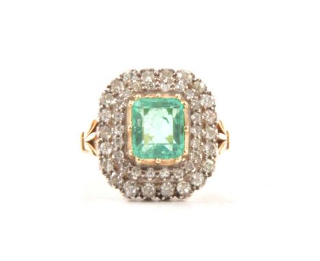 An emerald and diamond cluster ring, the rectangular step cut emerald, claw and collet set in yellow metal and surrounded by 