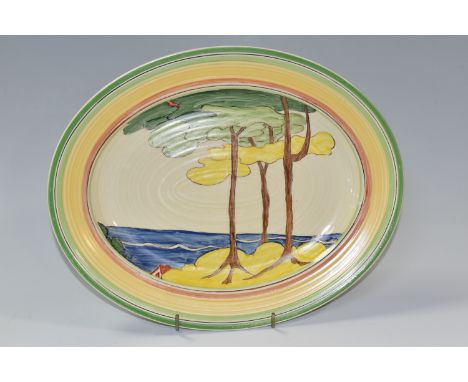 A NEWPORT POTTERY OVAL 'GREEN FIRS' PATTERN MEAT PLATE, painted with stylised tree in a coastal landscape, inside bands of re