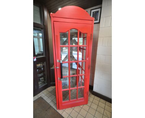 A BESPOKE RED PAINTED PINE TELEPHONE BOX, with a single swing door, glass front and sides, panel back depicting various newsp