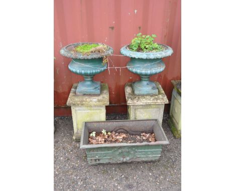 A PAIR OF EARLY 20TH CENTURY CAST IRON PAINTED URNS ON COMPOSITE SQUARE STANDS the urns are baluster with egg and dart top ed