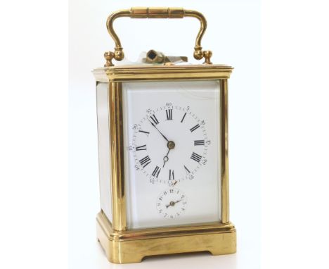 A brass frame carriage clock with white enamel face, Roman and Arabic numerals and subsidiary alarm dial. Eight-day, two-trai