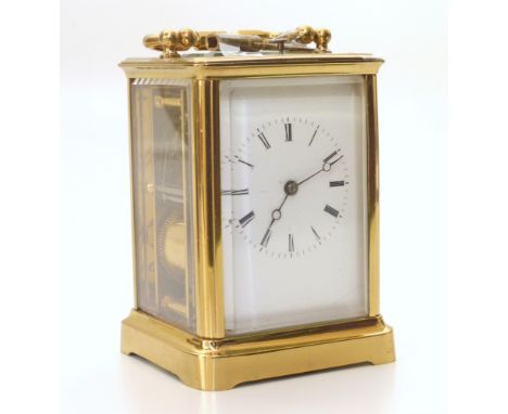 A brass frame carriage clock with white enamel face and Roman numerals, bevelled glass panels to sides. Eight-day, two-train 