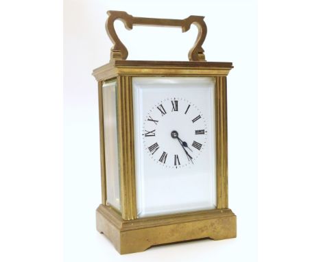 A brass frame carriage clock with swan-neck carry handle. White enamel face with Roman numerals. Eight-day, single train move