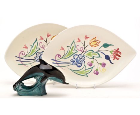 A pair of Poole Pottery oval dishes, decorated floral designs, 30.5cms (12in.); and a Poole Pottery dolphin ornament, 18cms (