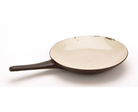Dame Lucie Rie: a glazed stoneware skillet, in light and dark brown glaze, tapering handle with incised decoration, with mark