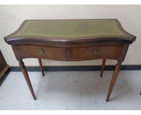 A Regency style mahogany serpentine fronted turnover top tea table with a green leather inset panel on raised legs, 76.5 cm h