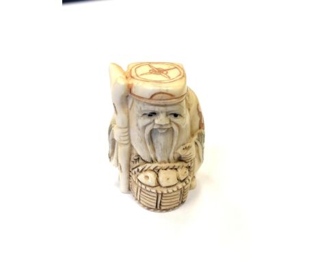 A Japanese carved bone netsuke - Village elder with a basket at his feet. 