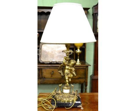A gilt metal lamp in the form of a putto with gathered cream shade and marble base 