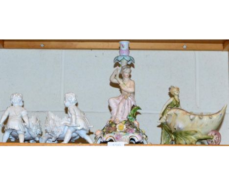 A Continental porcelain figural candlestick; a pair of blanc de chine models of putti within a wheelbarrow and a further Cont