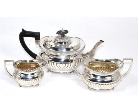 An Edwardian three piece silver tea service, of oval part fluted design