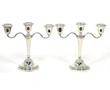 A pair of silver three light candleabra, Elkington & Co, Birmingham 1967, with laurel borders, filled, 20cm high