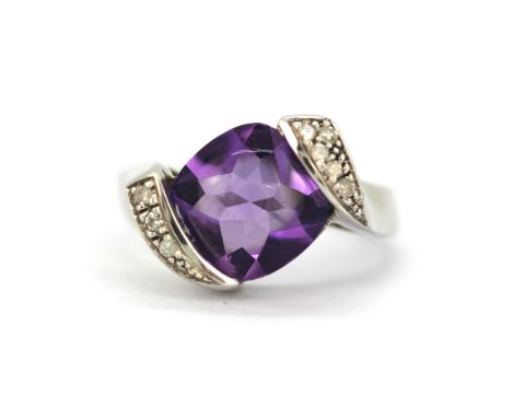 A 9ct white gold ring set with a large cabochon cut amethyst with brilliant cut diamond set shoulders, (N).