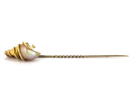 A yellow metal (tested 18ct gold and 9ct gold pin) shell mounted stick pin, L. 8.5cm.