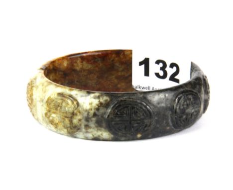 A Chinese carved mixed colour jade bangle.