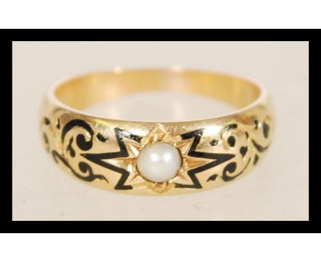 A 19th century Victorian 9ct gold ring set with a pearl having black enamel inlay within a scrolled engraving. Weight is 3.3 