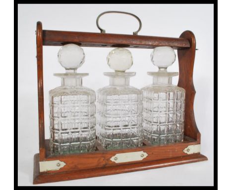 A 19th century Victorian oak triple decanter Tantalus having silver plated mounts. Complete with three faceted glass decanter