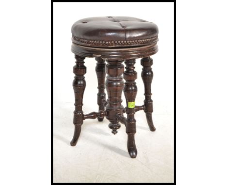 A Victorian mahogany revolving piano stool with splay turned supports with a leather button back stuffed studded seat pad. Me