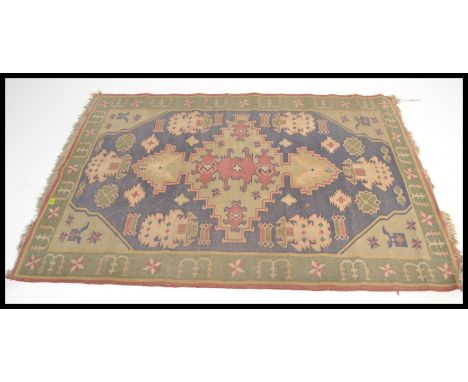 A vintage early 20th century floor carpet rug having a green and blue ground with geometric panels and medallions. Please see