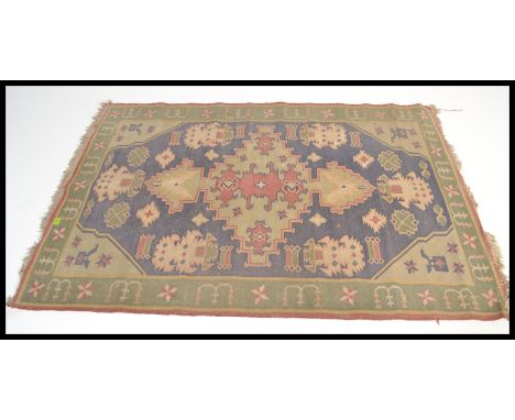 A vintage early 20th century floor carpet rug having a green and blue ground with geometric panels and medallions. Please see