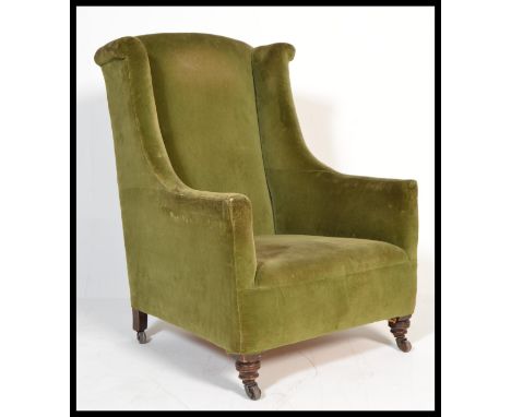 A 19th century Victorian mahogany wing back armchair with turned legs and ceramic castors upholstered in green velour.