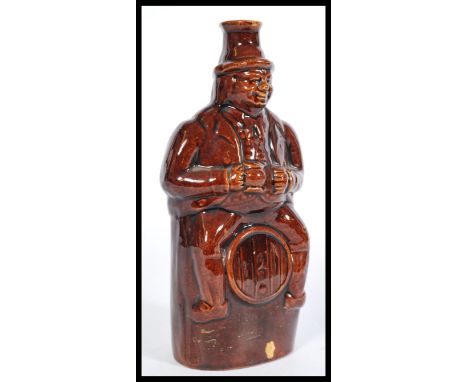 A 19th century salt glazed stoneware bottle flask depicting a Victorian man sitting on a barrel with a stein of ale.&nbsp;mea