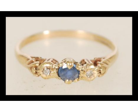 A 20th century hallmarked&nbsp; 9ct gold ladies ring with a central blue stone flanked by two diamonds in decorative prong se